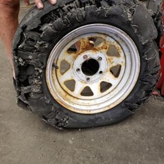 Badly damaged RV tire on a rim.